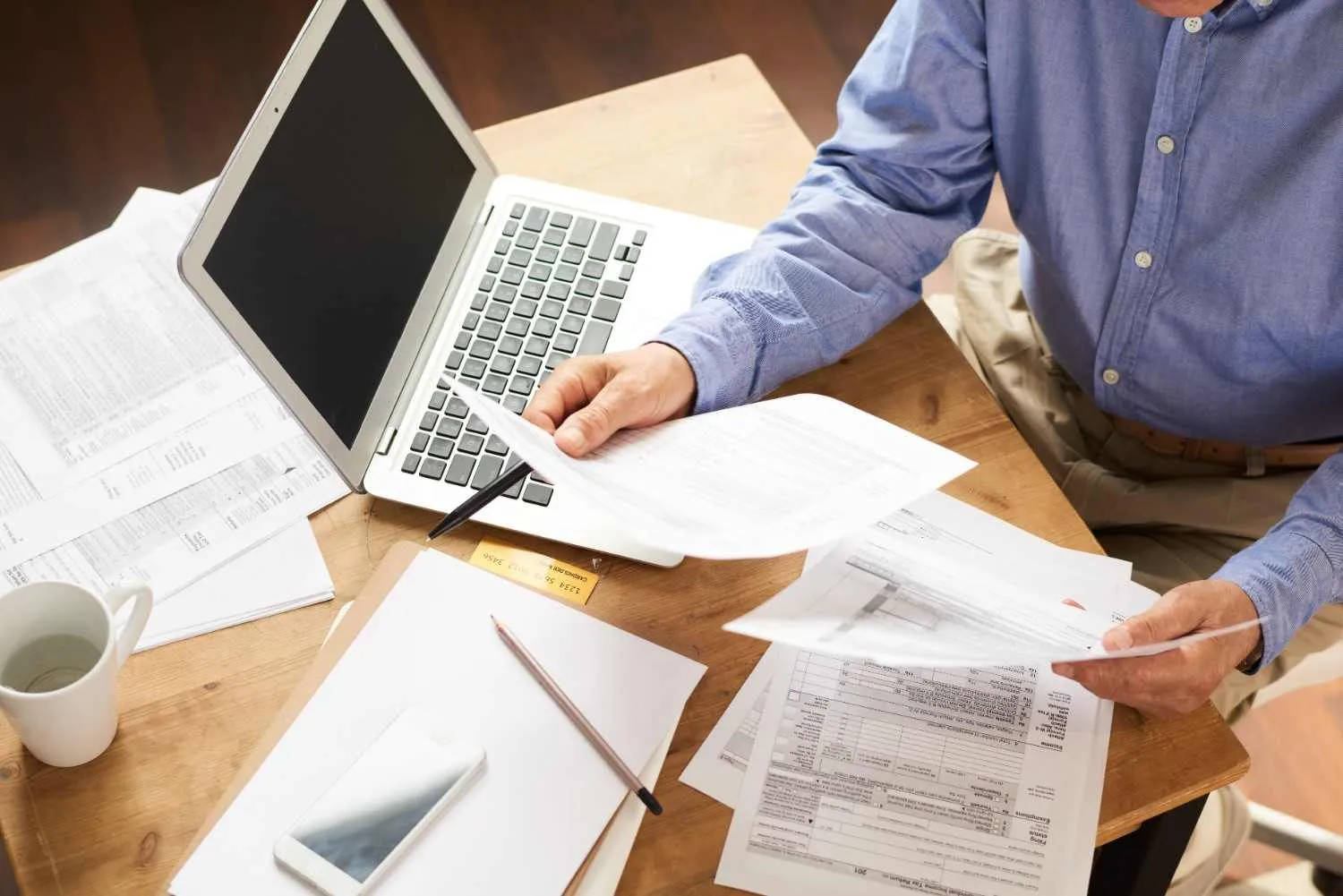 Solar bills, contract pages and a laptop spread across a table